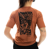 Person wearing a brown t-shirt with black graphic design on the back, brand 'Braw' visible.