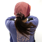 Person wearing a pink cap and blue jacket with a patterned design on a white background