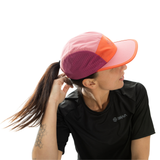 Person wearing a colorful cap and black shirt with a brand logo on a white background